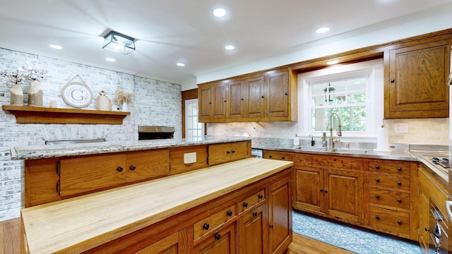 kitchen with decorative backsplash, crown molding, sink, and light hardwood / wood-style flooring