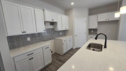 kitchen with pendant lighting, sink, decorative backsplash, and white cabinets