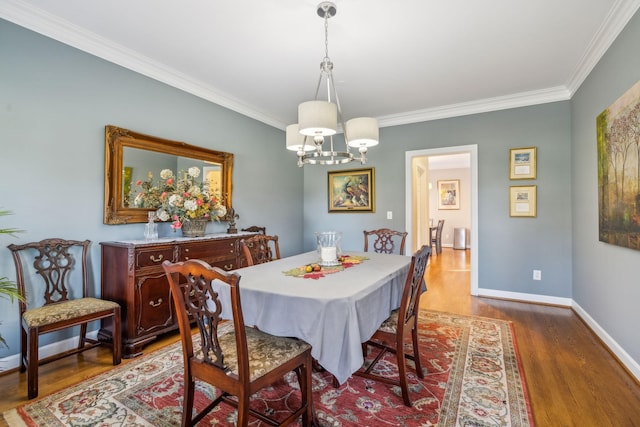 dining space with hardwood / wood-style flooring, crown molding, and a notable chandelier