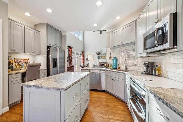 kitchen with gray cabinetry, sink, a center island, light hardwood / wood-style floors, and appliances with stainless steel finishes