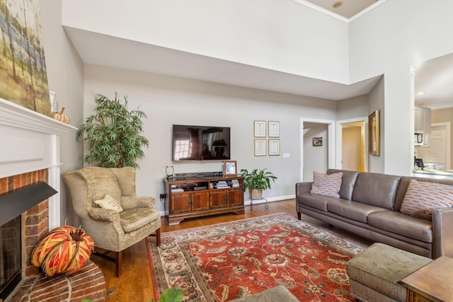 living room featuring hardwood / wood-style floors, crown molding, a fireplace, and a high ceiling