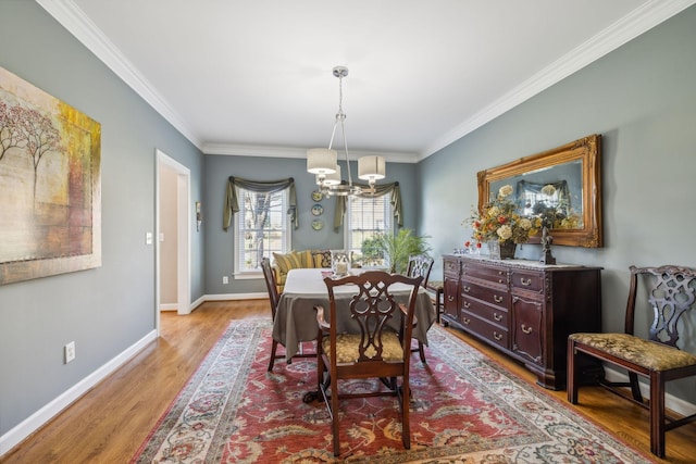 dining space featuring light wood-type flooring, ornamental molding, and an inviting chandelier