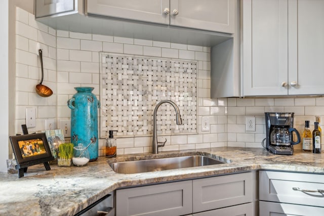 kitchen featuring dishwasher, tasteful backsplash, light stone counters, and sink