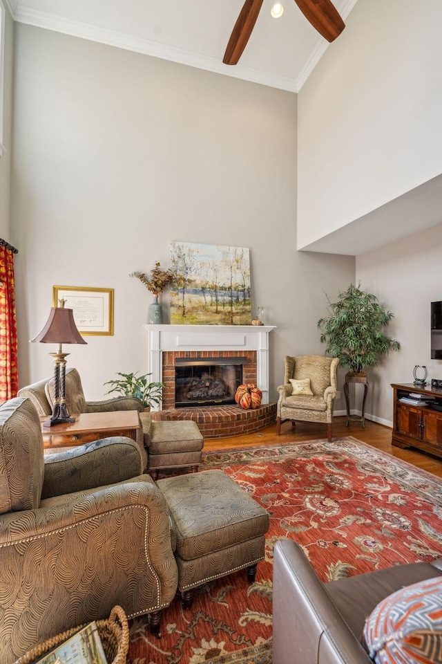 living room with hardwood / wood-style flooring, ceiling fan, crown molding, and a fireplace