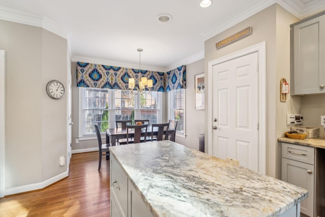 kitchen with gray cabinetry, hardwood / wood-style floors, a chandelier, pendant lighting, and ornamental molding