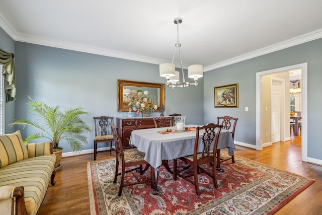 dining room featuring hardwood / wood-style floors, an inviting chandelier, and crown molding