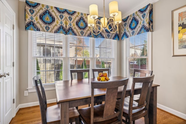 dining room featuring a chandelier, wood-type flooring, crown molding, and a healthy amount of sunlight