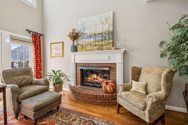 sitting room featuring wood-type flooring and a brick fireplace