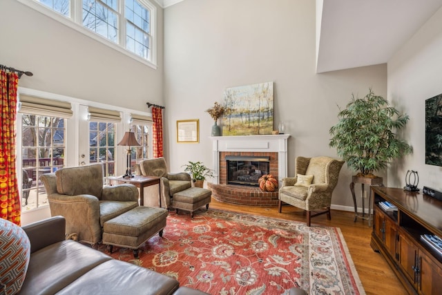 living room with a fireplace, a high ceiling, and hardwood / wood-style flooring