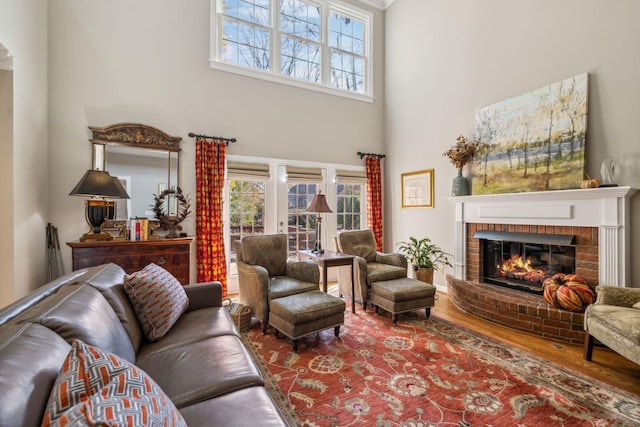 living room with wood-type flooring, a high ceiling, and a brick fireplace