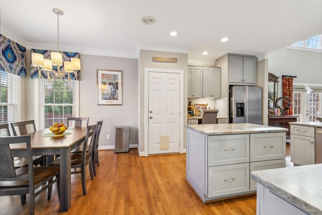 kitchen with pendant lighting, a center island, stainless steel fridge, gray cabinets, and ornamental molding