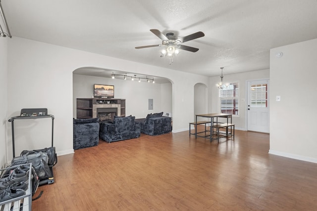 living room featuring a textured ceiling, a tiled fireplace, hardwood / wood-style floors, and ceiling fan with notable chandelier