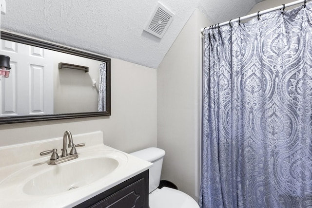 bathroom featuring vaulted ceiling, vanity, a textured ceiling, and toilet