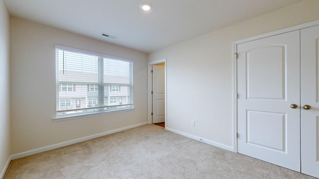 unfurnished bedroom featuring light carpet and a closet