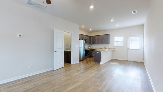 kitchen with sink, light hardwood / wood-style flooring, dark brown cabinets, kitchen peninsula, and stainless steel refrigerator