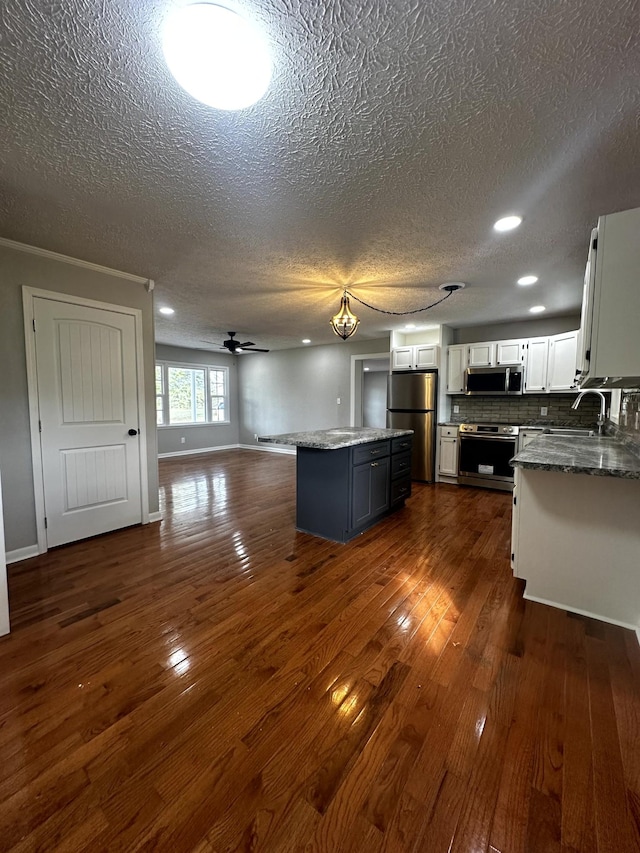 kitchen with tasteful backsplash, stainless steel appliances, ceiling fan, a center island, and white cabinetry