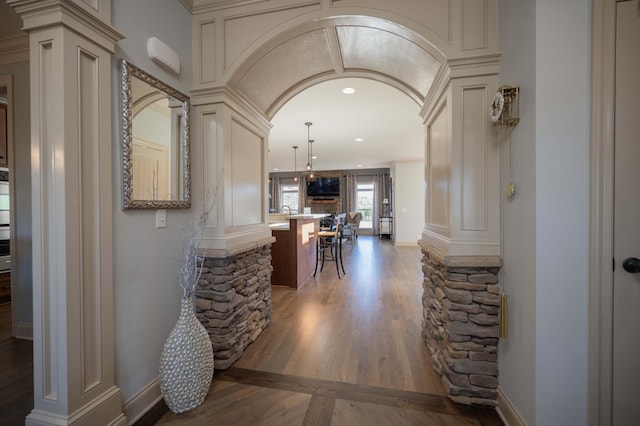 hall with ornate columns and dark wood-type flooring