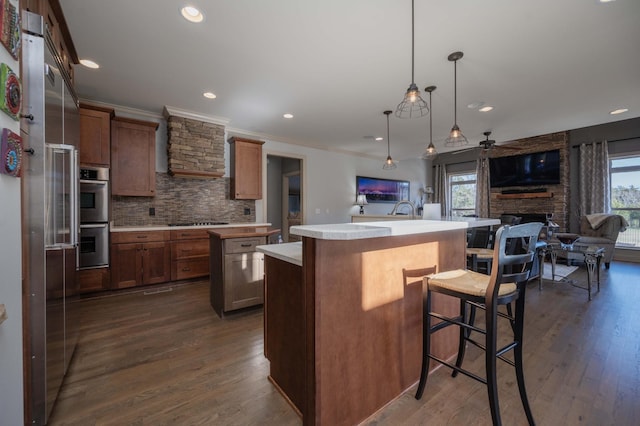 kitchen with decorative backsplash, pendant lighting, stovetop, a fireplace, and a center island