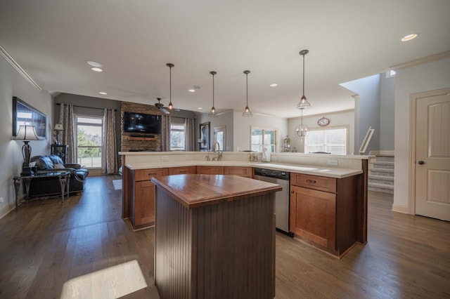 kitchen with stainless steel dishwasher, ceiling fan, sink, decorative light fixtures, and a kitchen island