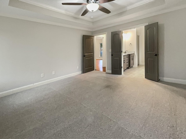 unfurnished bedroom with a raised ceiling, ceiling fan, light colored carpet, and ensuite bathroom