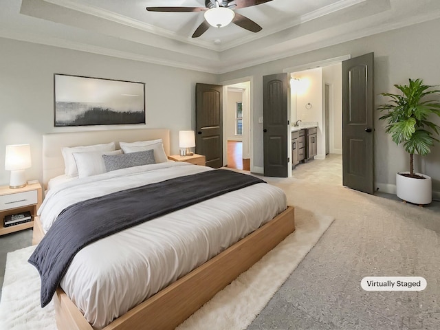 bedroom with ceiling fan, a raised ceiling, light carpet, and ensuite bath