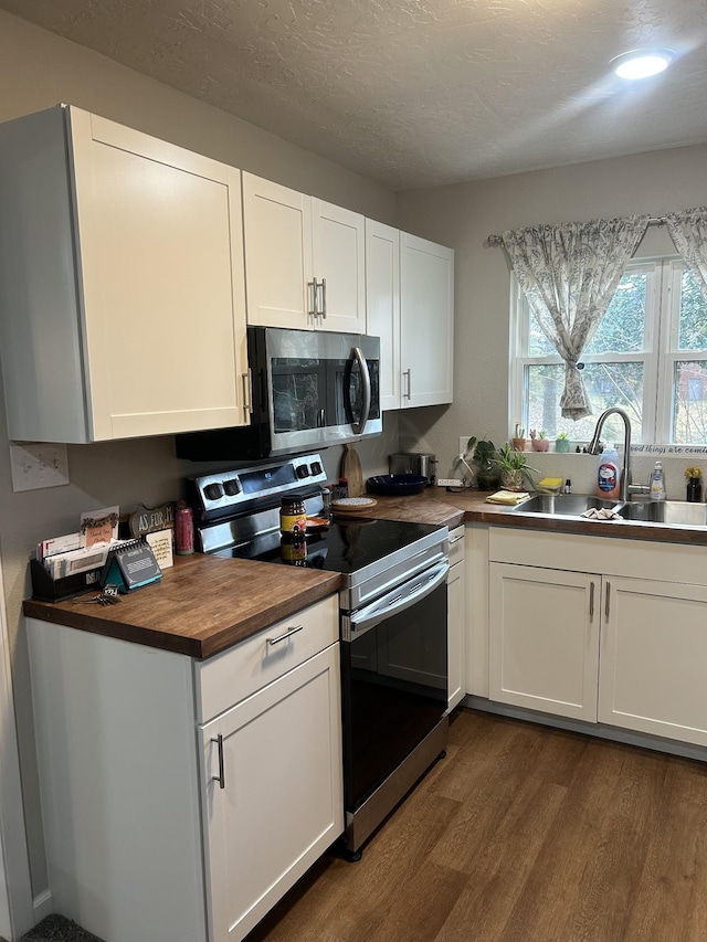 kitchen with white cabinets, wood counters, sink, and stainless steel appliances