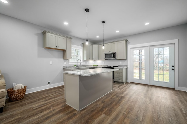 kitchen with hanging light fixtures, light stone countertops, gray cabinets, and sink