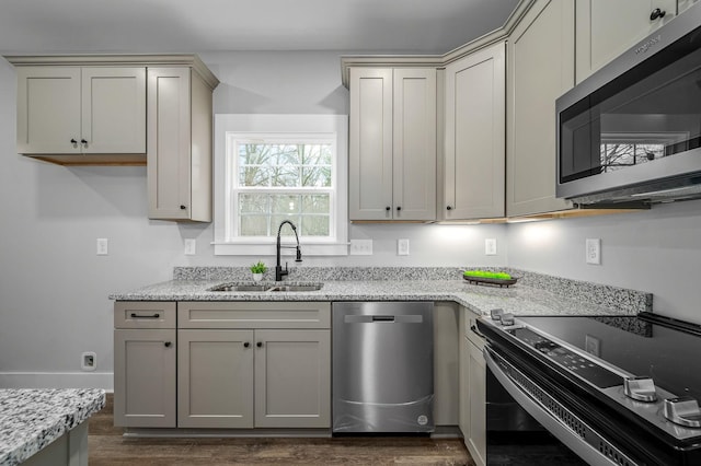 kitchen with dark hardwood / wood-style floors, appliances with stainless steel finishes, sink, and light stone counters