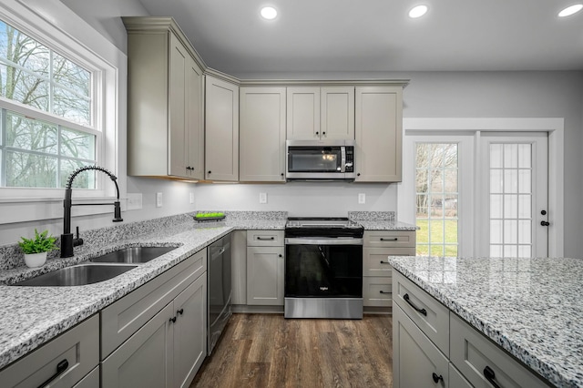 kitchen featuring sink, gray cabinetry, dark hardwood / wood-style flooring, stainless steel appliances, and light stone countertops