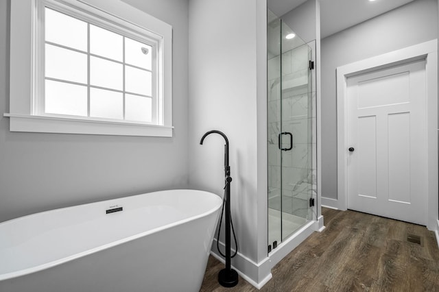 bathroom with hardwood / wood-style flooring and shower with separate bathtub