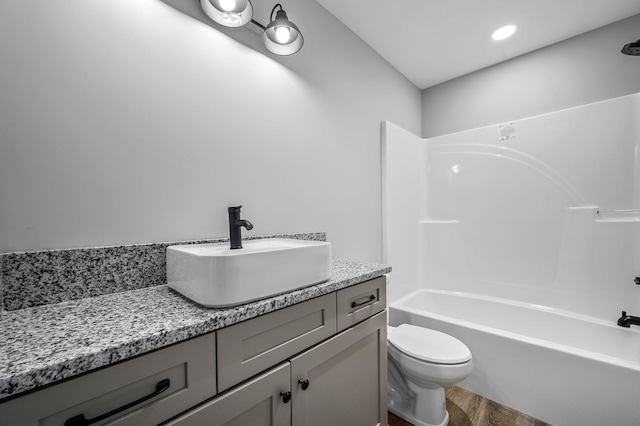 full bathroom featuring hardwood / wood-style flooring, vanity, shower / bath combination, and toilet