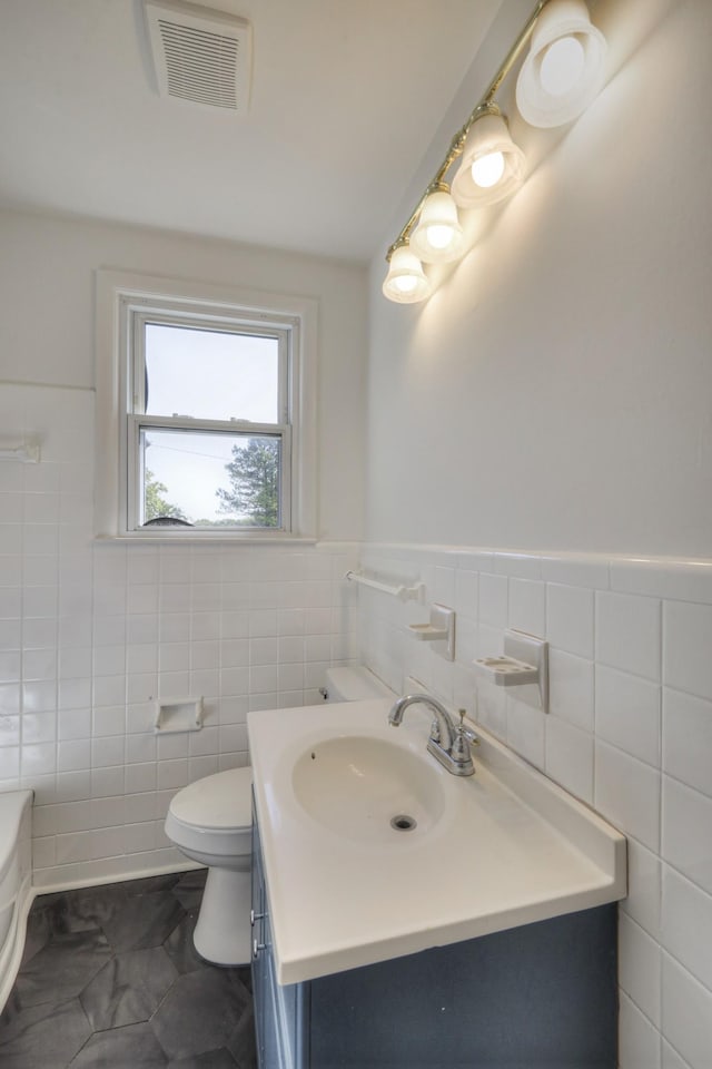 bathroom with vanity, tile walls, and toilet