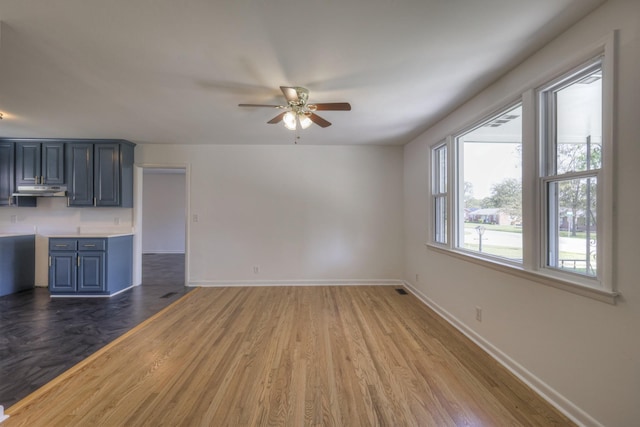 unfurnished living room featuring ceiling fan and dark wood-type flooring