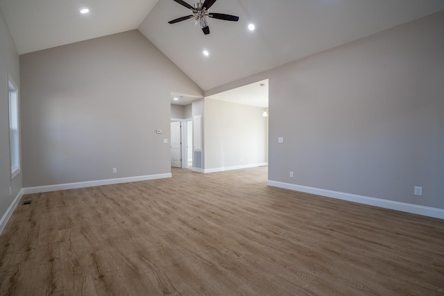 empty room featuring baseboards, wood finished floors, high vaulted ceiling, and ceiling fan