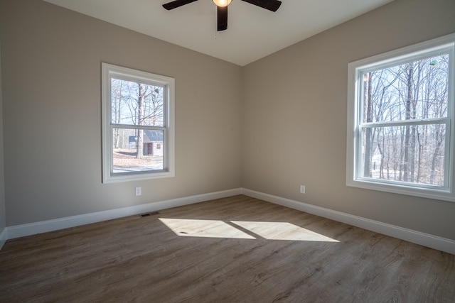 spare room featuring wood finished floors, baseboards, visible vents, and ceiling fan