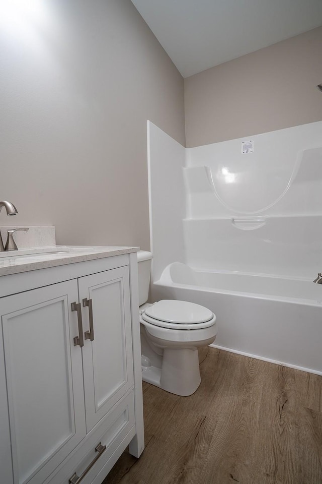 bathroom with toilet, vanity, bathing tub / shower combination, and wood finished floors