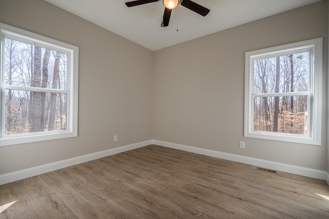 empty room with visible vents, ceiling fan, baseboards, and wood finished floors