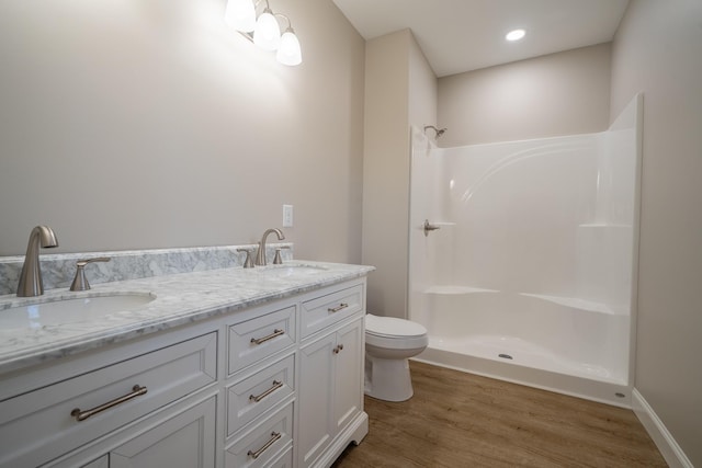 bathroom with wood finished floors, toilet, a shower, and a sink