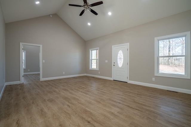 foyer entrance with a ceiling fan, baseboards, wood finished floors, visible vents, and high vaulted ceiling