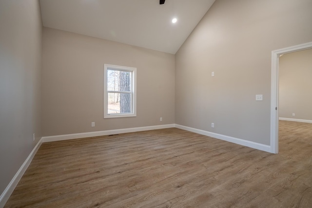 spare room featuring visible vents, high vaulted ceiling, wood finished floors, recessed lighting, and baseboards