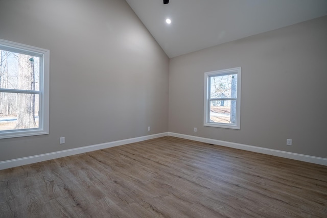 spare room featuring recessed lighting, wood finished floors, baseboards, and high vaulted ceiling