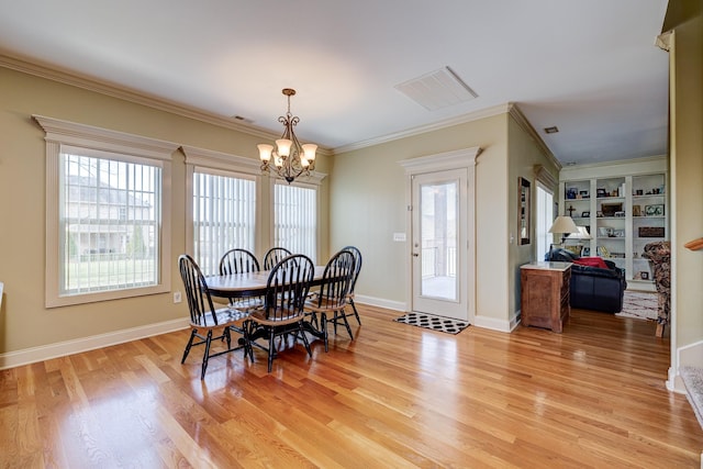 dining space featuring built in features, light hardwood / wood-style flooring, an inviting chandelier, and ornamental molding