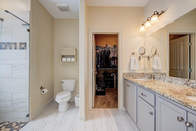 bathroom with toilet, vanity, and tiled shower