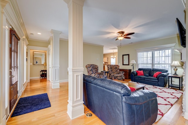 living room with decorative columns, crown molding, ceiling fan with notable chandelier, and light wood-type flooring