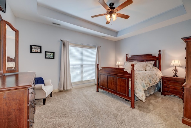 carpeted bedroom featuring ceiling fan and a tray ceiling