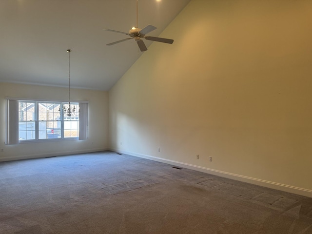 carpeted empty room with ceiling fan with notable chandelier and high vaulted ceiling