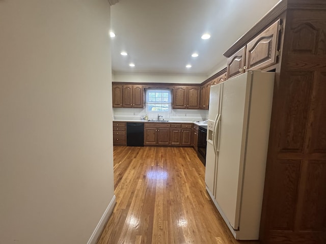 kitchen featuring light wood-type flooring, sink, and black appliances