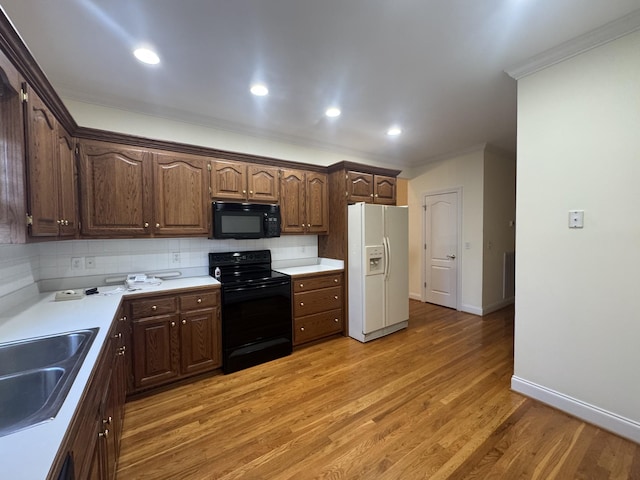 kitchen with tasteful backsplash, ornamental molding, sink, black appliances, and wood-type flooring