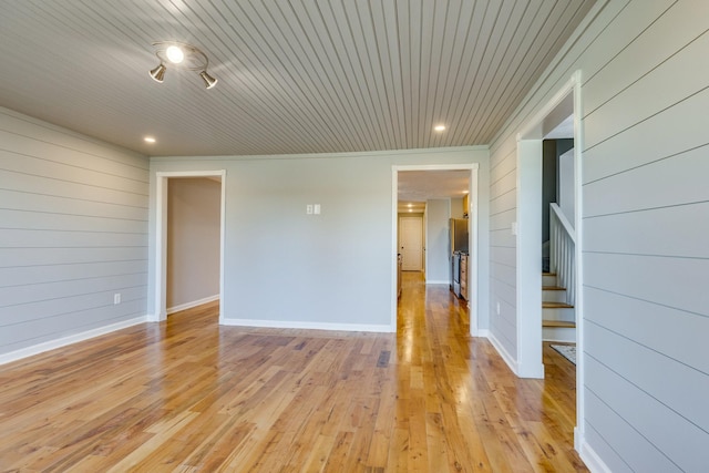 unfurnished room with wood walls, wooden ceiling, and light hardwood / wood-style flooring