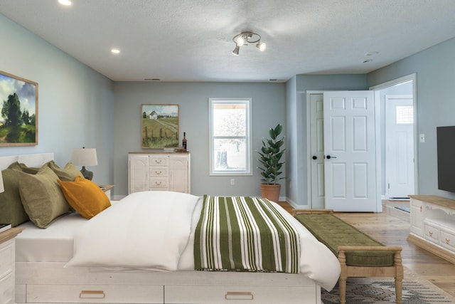 bedroom with a textured ceiling and light wood-type flooring